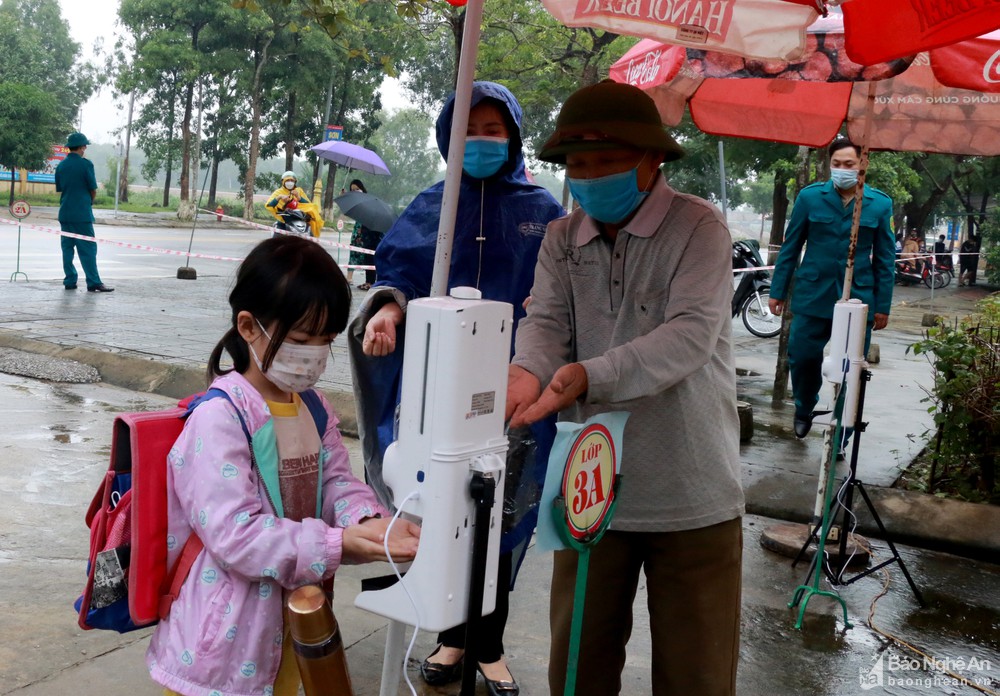 Học sinh Trường Tiểu học Nghi Thu rửa tay sát khuẩn và đo thân nhiệt bằng máy tự động. Ảnh: Mỹ Hà